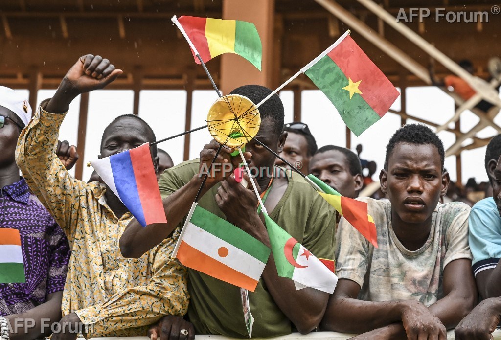 Un homme brandit des drapeaux de Mali, du Burkina Faso, d'Algérie, du Niger et de Russie, lors d'un rassemblement au stade de Niamey, le 26 août 2023.