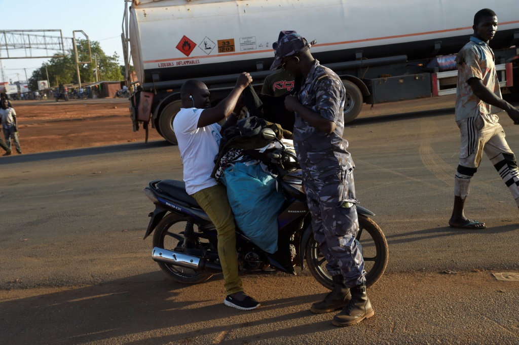Un policier fouille un vendeur à moto à Cinkassé, un poste frontalier commercial du nord du Togo avec le Burkina Faso, le 16 février 2020.