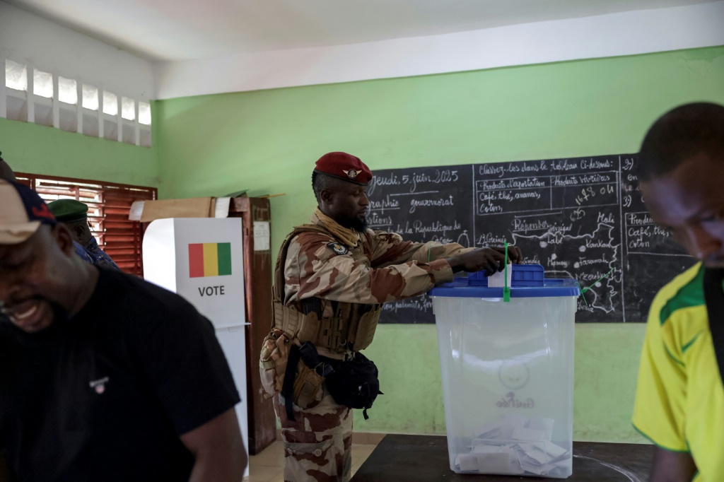 Un soldat guinéen dépose son bulletin dans une urne d'un bureau de vote dans une école de Conakry, le 21 septembre 2025, lors d'un référendum constitutionnel en Guinée.