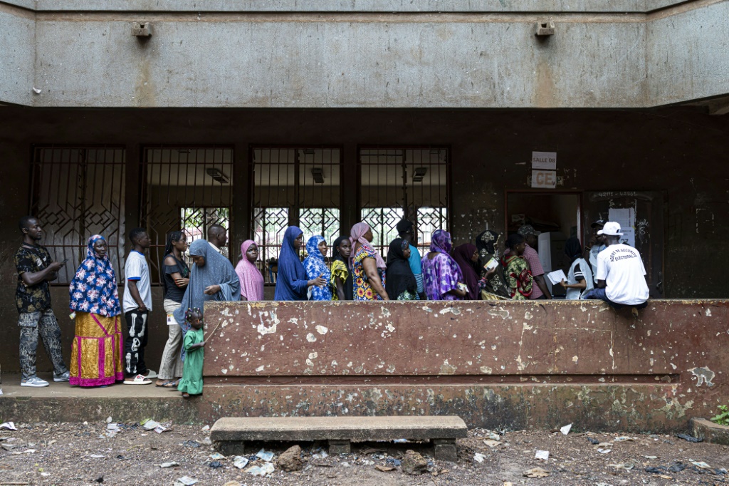 Des électeurs font la queue devant un bureau de vote installé dans une école primaire de la capitale guinéenne Conakry, le 21 septembre 2025. Les Guinéens ont voté en nombre dimanche, 21 septembre sur un projet de Constitution soumis par la Transition et visant au retour à l'ordre constitutionnel, quatre ans après la prise de pouvoir par les militaires.