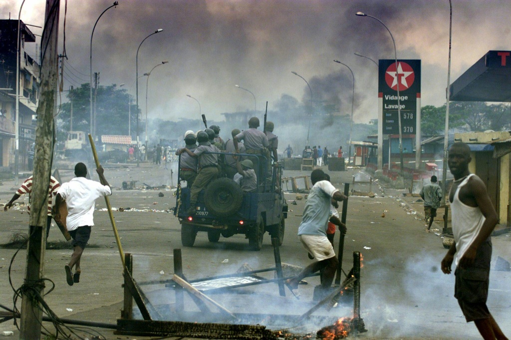 Des partisans du chef de l'opposition ivoirienne, Alassane Ouattara, érigent des barricades, le 26 octobre 2000 à Abidjan, tandis que la Police tente de les disperser ainsi que ceux du Front populaire ivoirien de Laurent Gbagbo (en arrière-plan) lors de manifestations contre la légitimité de l'élection présidentielle du 22 octobre de cette année-là.