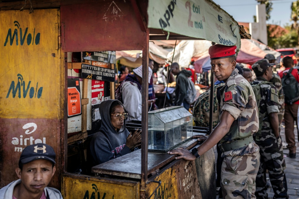 Au lendemain de la prise de pouvoir, un soldat de l'unité CAPSAT discute avec une vendeuse près de sa base militaire à Antananarivo, le 15 octobre 2025.