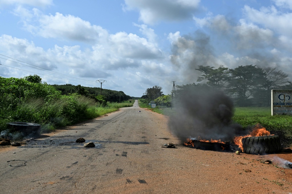 Des pneus brûlés faisant partie de barricades bloquant la route menant au village de Lopou, en Côte d'Ivoire, le 25 octobre 2025.