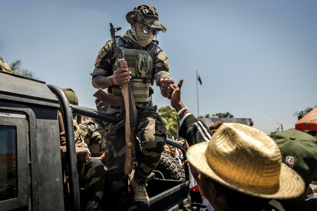 Un militaire malgache salue du poing un civil alors que des manifestants se rassemblent pour un meeting de la société civile devant l'hôtel de ville d'Antananarivo, le 13 octobre 2025.