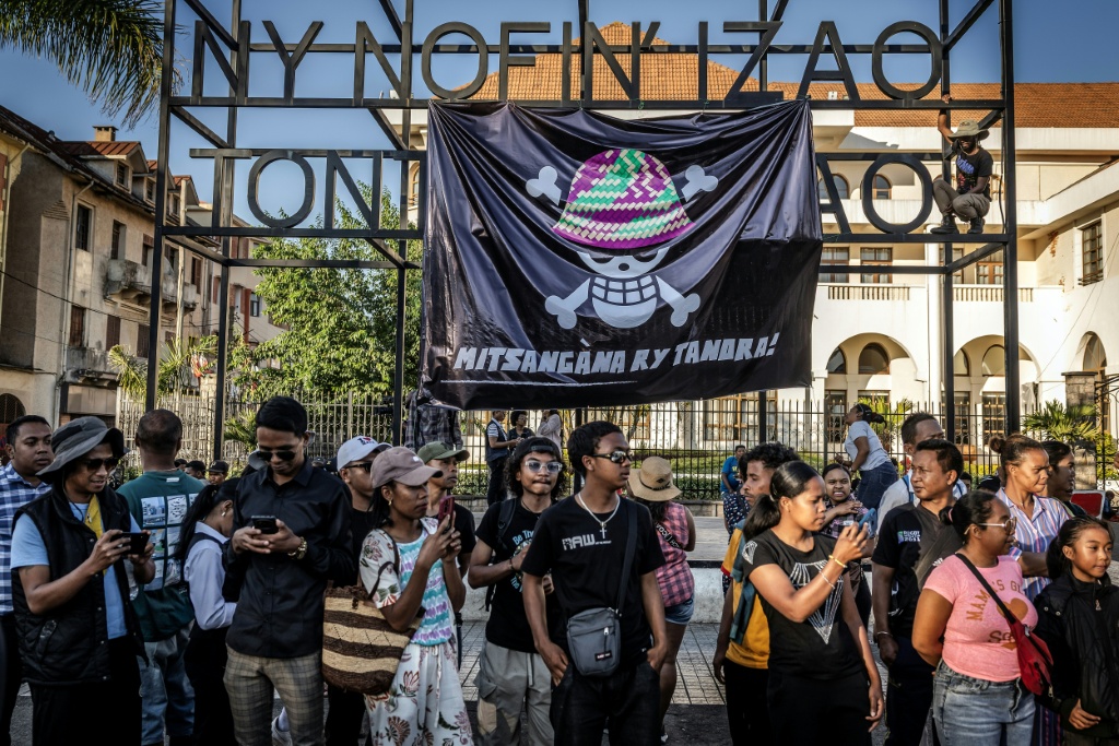 Des habitants se rassemblent alors que des jeunes installent une banderole portant la version malgache du logo du populaire manga japonais One Piece, un symbole adopté par les mouvements Gen Z à travers le monde, à Antananarivo le 12 octobre 2025.