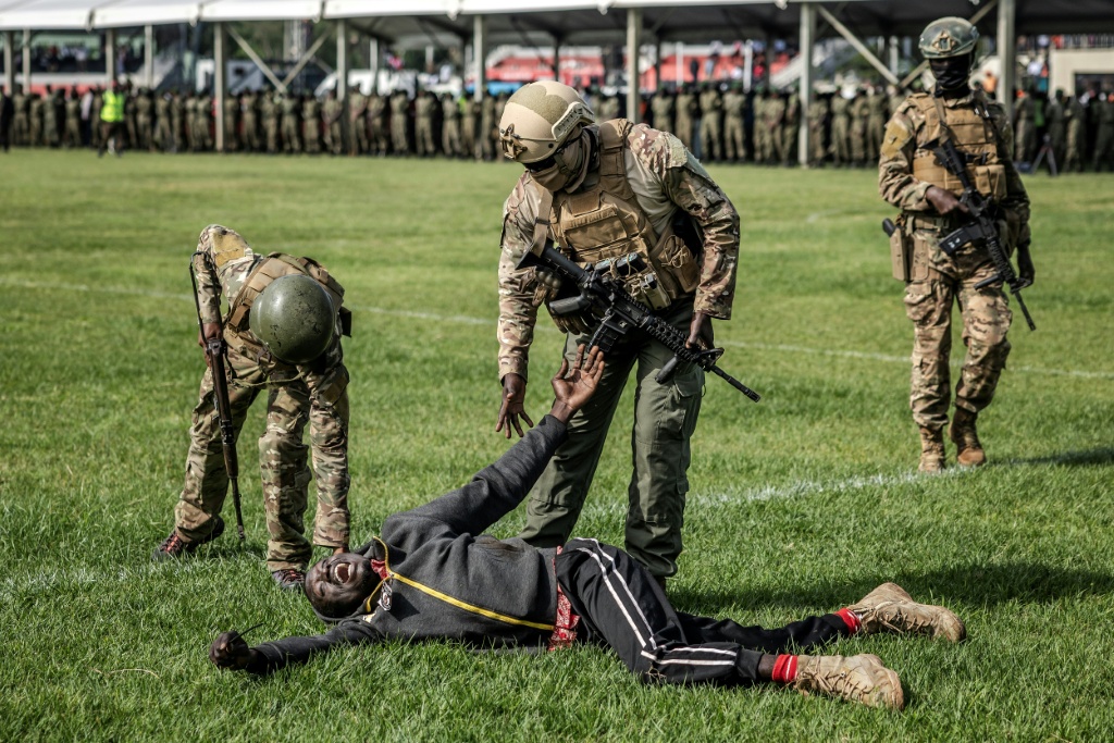 Des membres des Forces de l'ordre du Kenya assistent un partisan de l'opposant Raila Odinga, dans le stade où son corps est exposé, à Kisumu, le 18 octobre 2025.
