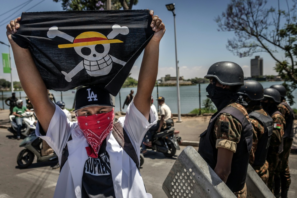 Un drapeau portant le logo du célèbre manga japonais One Piece, symbole adopté par les mouvements de protestation de la génération Z dans le monde entier, devant les forces de sécurité lors d'une manifestation exigeant de meilleures conditions de santé et des réformes constitutionnelles à Antananarivo, le 7 octobre 2025 à Madagascar.