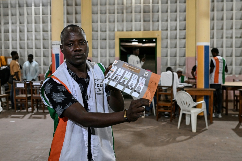 Un représentant de la Commission électorale montre un bulletin de vote pour la présidentielle ivoirienne, à Abidjan le 25 octobre 2025.