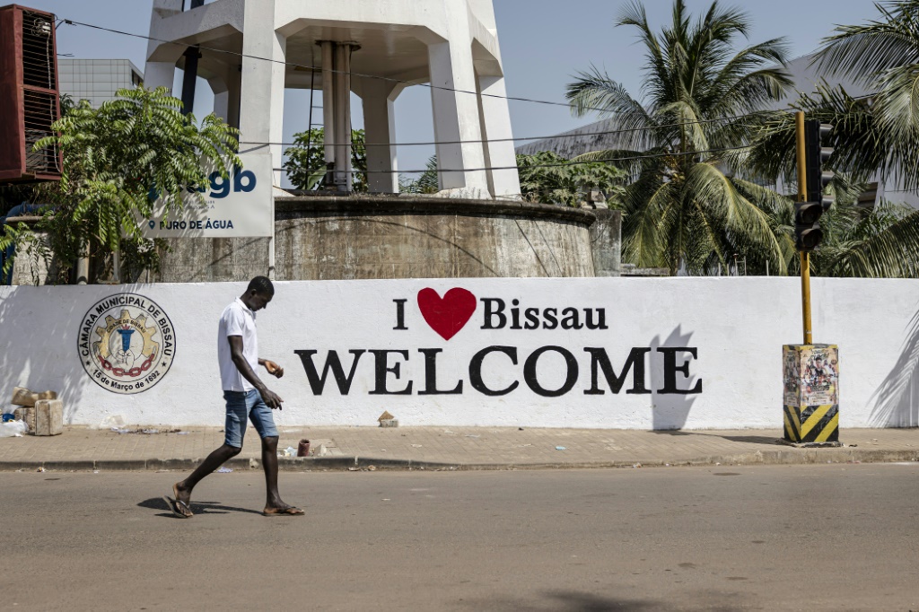 Un piéton passe devant une fresque dans la capitale bissau-guinéenne le 27 novembre 2025. Une junte a pris le pouvoir en Guinée-Bissau, alors que le pays était dans l'attente des résultats des élections présidentielle et législatives du 23 novembre.