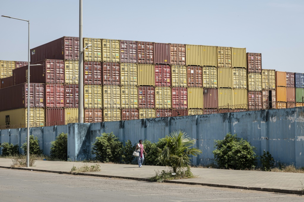 Un piéton passe devant des containers empilés au Port de Bissau le 26 novembre 2025. Une junte a pris le pouvoir en Guinée-Bissau, alors que le pays était dans l'attente des résultats des élections présidentielle et législatives du 23 novembre.