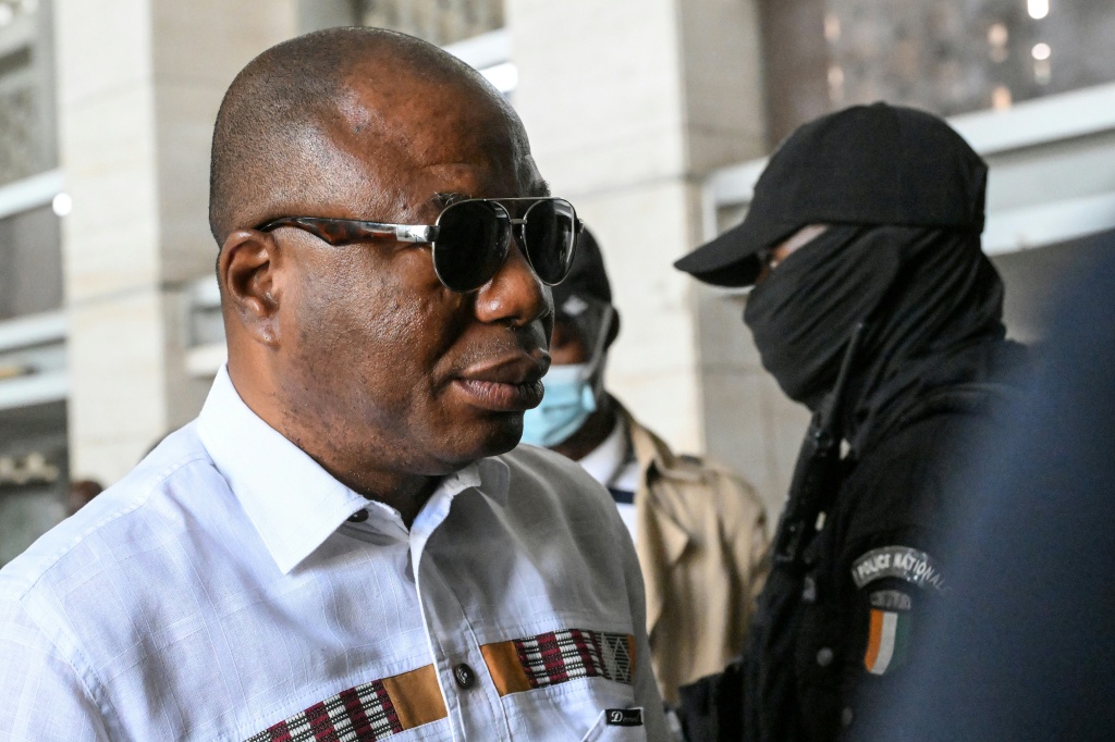 Damana Pickass (g), membre du Parti populaire africain (PPA-CI, opposition) de l'ancien Président ivoirien Laurent Gbagbo, arrive au Tribunal d'Abidjan, le 12 février 2025, pour le verdict de son procès pour l'attaque d'une caserne militaire en 2021.