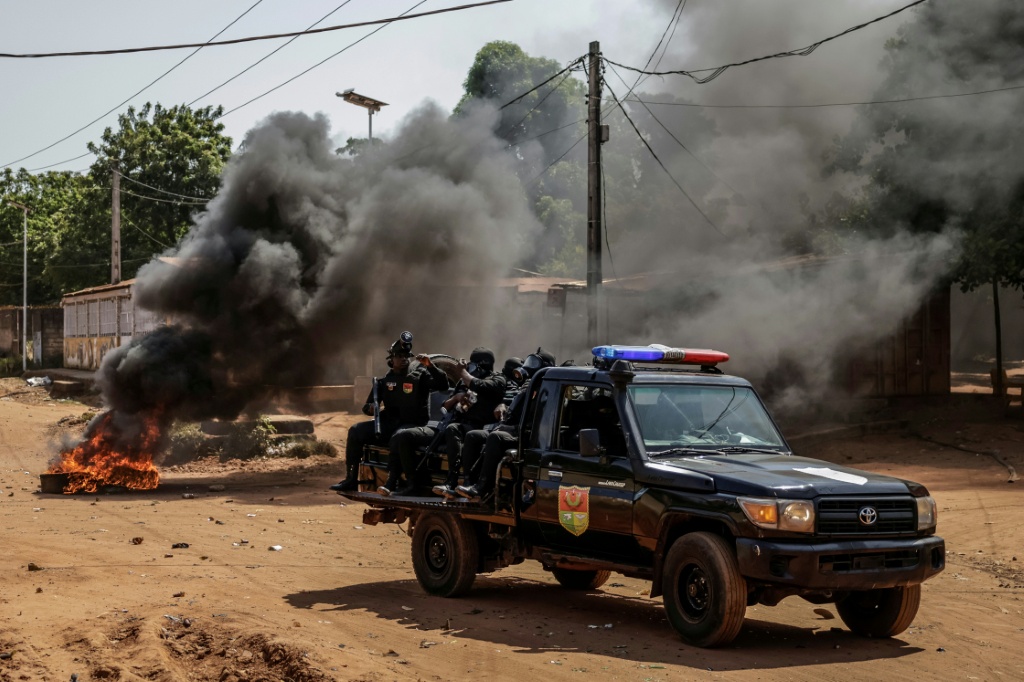 Un véhicule des Forces de l'ordre passe à proximité de pneus enflammés lors d'échauffourées dans la capitale bissau-guinéenne, le 29 novembre 2025.