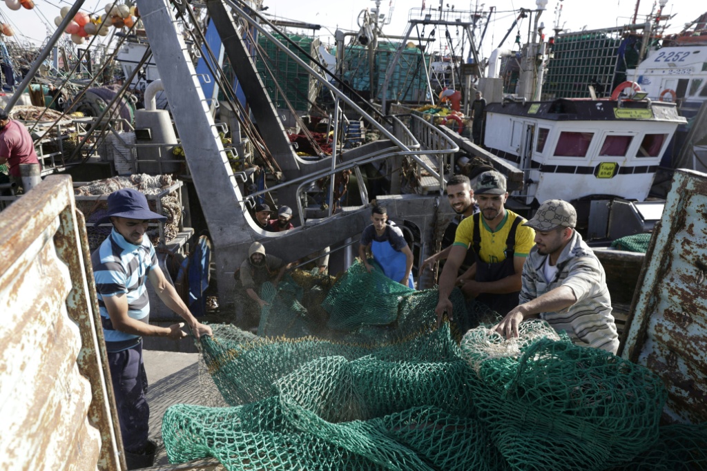 Des pêcheurs déploient un grand filet sur le pont de leur bateau amarré dans le Port de Laâyoune, principale ville du Sahara sous contrôle marocain, le 6 novembre 2025.