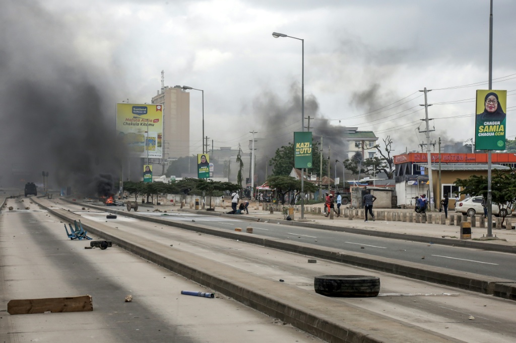 Des manifestants se précipitent pour aider un blessé près de barricades en feu, pendant des affrontements à Dar es Salaam (Tanzanie) le 29 octobre 2025, pendant les élections présidentielle et législatives.
