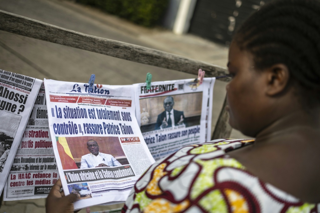 Une cliente regarde les titres des journaux devant un kiosque à Cotonou (Bénin), le 8 décembre 2025.