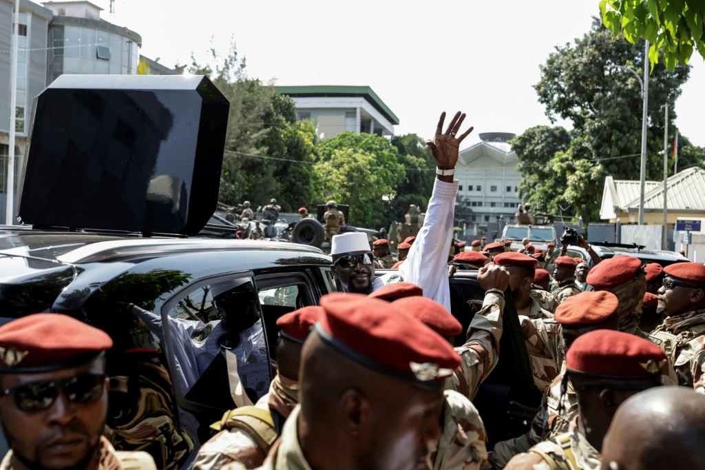 Le Président guinéen et candidat à la Présidence Mamadi Doumbouya (au centre) salue la foule après avoir voté à Conakry, le 28 décembre 2025, lors de l'élection présidentielle guinéenne.