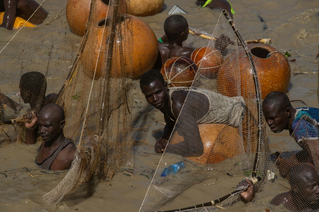 Un pêcheur flotte sur une calebasse tandis que d'autres pêcheurs tentent d'attraper des poissons dans la rivière Matan Fada lors du Festival culturel et de pêche d'Argungu, dans la ville d'Argungu, dans l'État de Kebbi, au nord-ouest du Nigeria, le 14 février 2026.