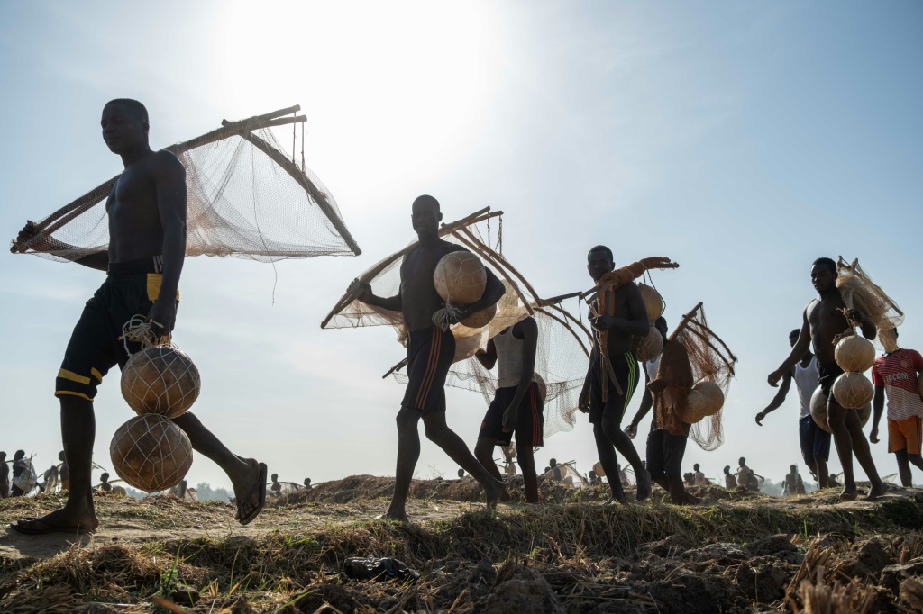 Des pêcheurs transportent des calebasses et des filets de pêche alors qu'ils se rendent à la rivière Matan Fada pour le Festival culturel et de pêche d'Argungu, dans la ville d'Argungu, dans l'État de Kebbi, au nord-ouest du Nigeria, le 14 février 2026.