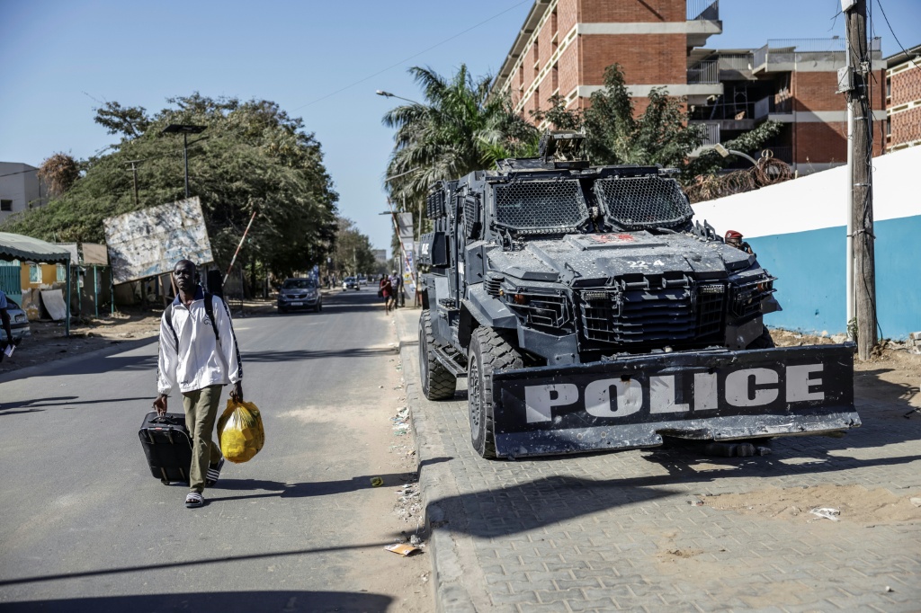 Un étudiant, transportant ses affaires, passe à côté d'un véhicule blindé de la Police alors qu'il quitte l'Université Cheikh Anta Diop, le 10 février 2026 à Dakar, au Sénégal.