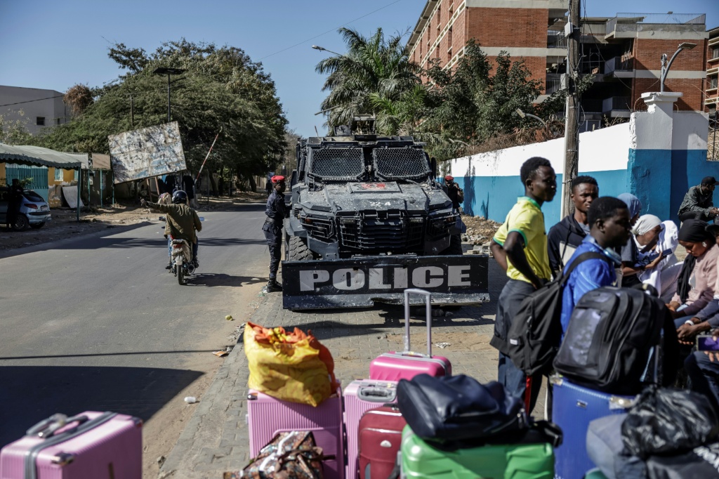 Un véhicule blindé de la Police sénégalaise est garé devant l'Université Cheikh Anta Diop, à Dakar (Sénégal), le 10 février 2026, à côté d'étudiants avec leurs bagages qui quittent l'Université.