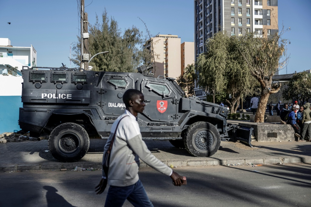 Un étudiant passe devant un véhicule blindé de la Police sénégalaise garé devant l'Université Cheikh Anta Diop, à Dakar, le 10 février 2026.
