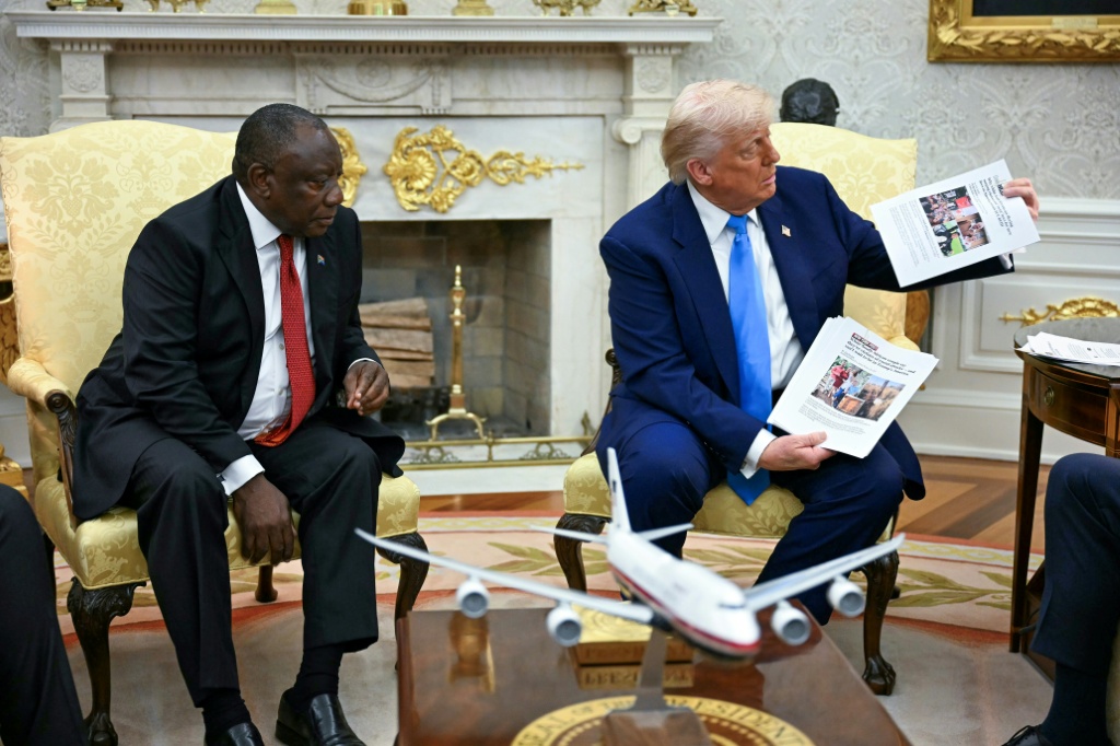 Le Président américain Donald Trump (d) montre des photos lors de sa rencontre avec le Président sud-africain Cyril Ramaphosa dans le Bureau ovale de la Maison Blanche, à Washington, le 21 mai 2025.
