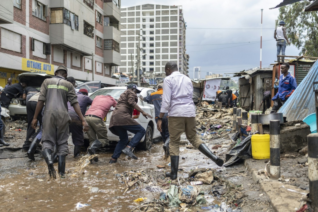Des habitants déplacent des véhicules endommagés après une nuit de fortes pluies ayant provoqué d'importantes inondations, le 7 mars 2026 à Nairobi, au Kenya.