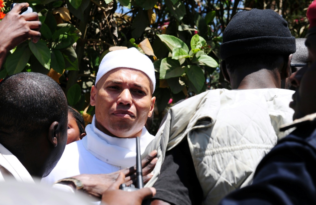 Karim Wade (c), fils de l'ancien Président du Sénégal, à l'issue de sa comparution devant le procureur anticorruption du pays pour justifier ses revenus face aux accusations de "richesse illégale", le 15 mars 2013.