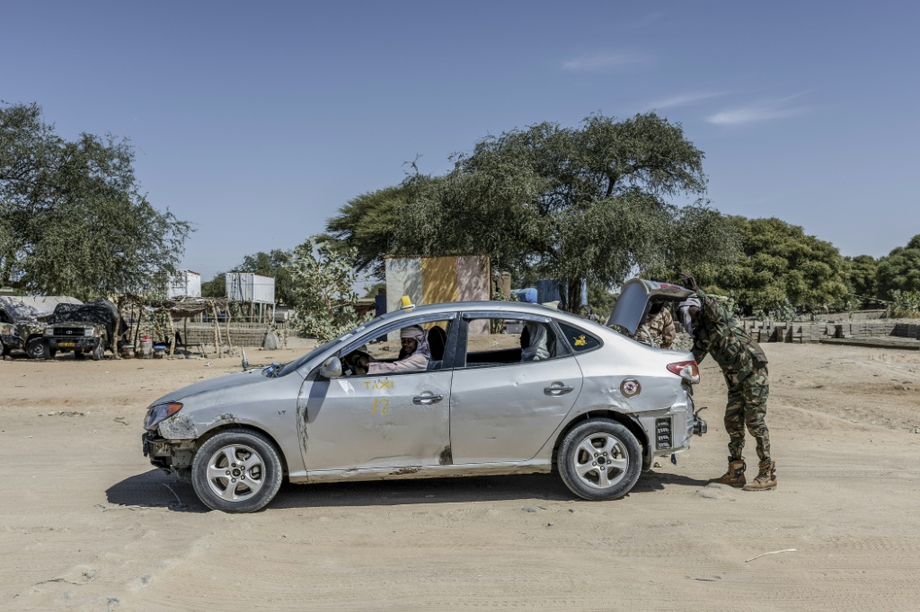 Des soldats tchadiens inspectent le coffre d'un taxi circulant entre le Tchad et le Soudan au poste frontière de Tiné, le 8 novembre 2025.
