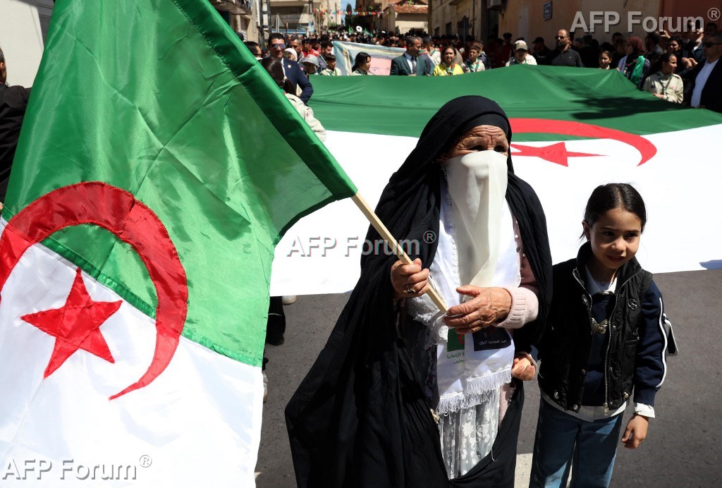 Une Algérienne tient le drapeau national lors de la commémoration des massacres de Sétif de 1945, à Sétif le 8 mai 2026.
