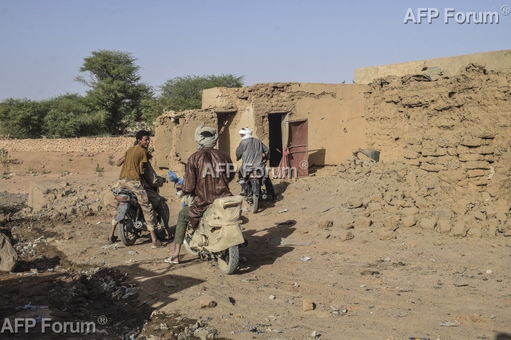 Des motocyclistes devant une maison détruite par une frappe de l'armée malienne, le 14 mai 2026 à Kidal, dans le nord du Mali