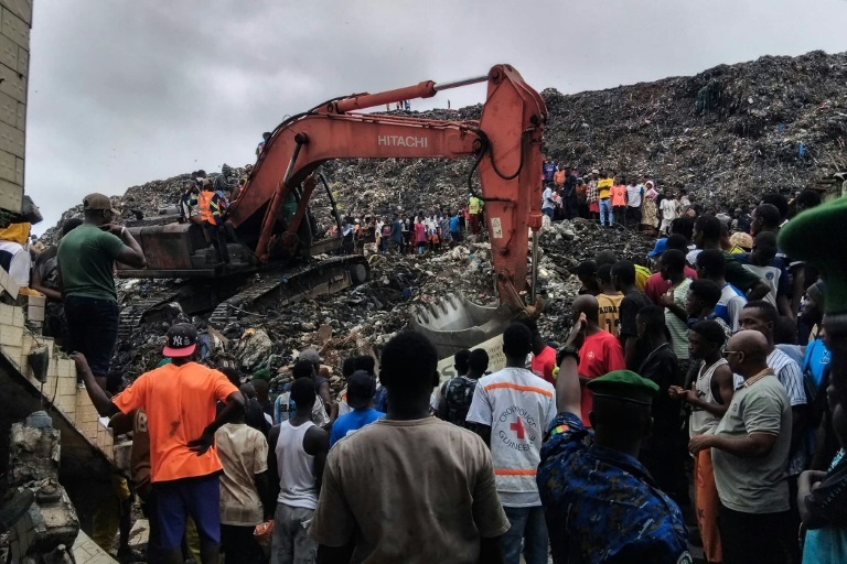 Une pelleteuse est utilisée pour rechercher des corps, après l'effondrement d'une décharge sur des habitations à Dar es salam dans la banlieue de Conakry, le 23 août 2026.
